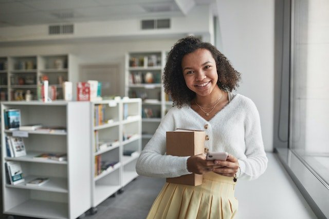 smiling woman in a library with books on low white shelves